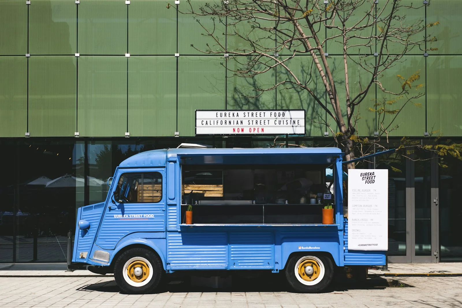 Un food truck bleu garé devant un immeuble
